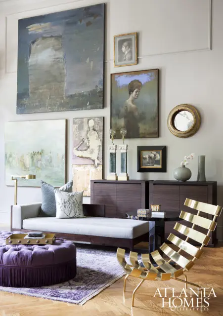 Living room with a light gray chaise lounge, purple tufted ottoman, abstract art, and a gold slatted chair.