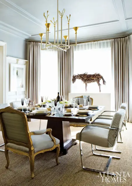 Formal dining room with a dark wood table set for dinner, upholstered chairs, a sculptural horse art piece, and a modern chandelier.