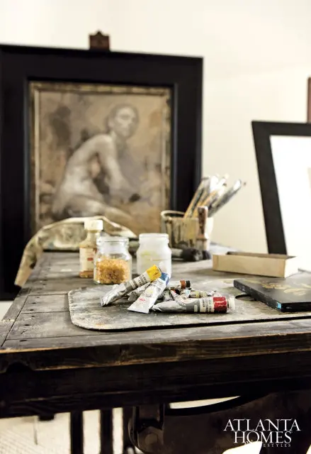 Tubes of oil paint scattered on a wooden artist's palette, with jars of pigment and brushes in the background.