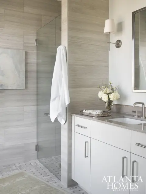 Modern bathroom with a glass-enclosed shower featuring wood-look tile walls, a white vanity with brushed nickel hardware, and a wall-mounted sconce.