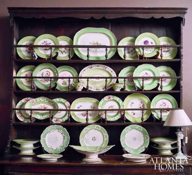 Dark wood hutch filled with green and white floral patterned china, including platters, plates, and serving bowls.