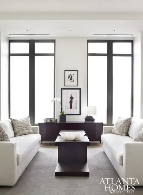 Living room with two white sofas facing each other, dark wood console table with artwork and lamp, and a dark wood coffee table with a marble bowl.