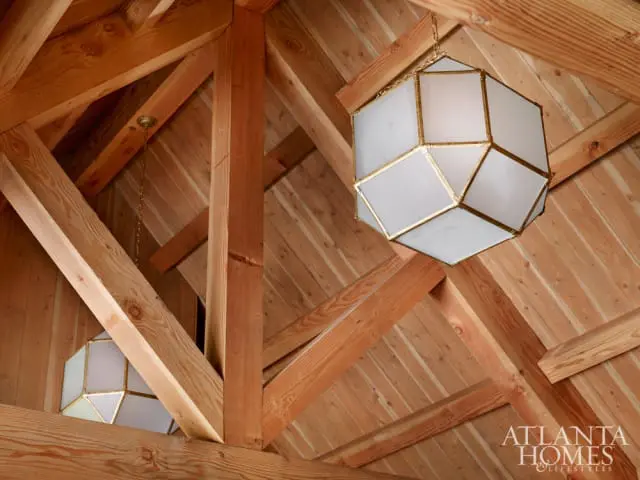 Wooden beamed ceiling with two geometric pendant lights featuring frosted glass panels and brass frames.