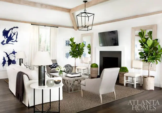 Living room with white slipcovered sofa, grey armchair, ornate grey coffee table, dark wood floors, and abstract blue wall art.