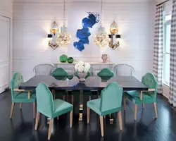 Dining room with dark wood table, teal velvet chairs, white paneled walls, abstract blue wall art, and checkered curtains.