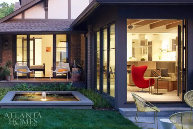 Modern kitchen with light wood cabinetry, stainless steel appliances, and a red egg chair in the adjacent living area.