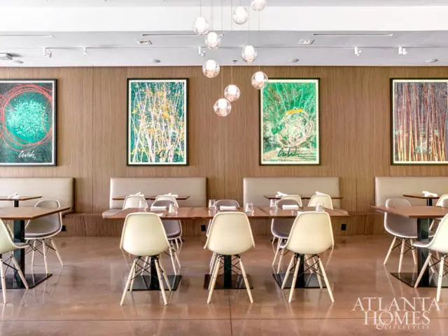 Dining room with wood-paneled walls, upholstered banquettes, and modern chairs around wooden tables. Abstract art adorns the walls.
