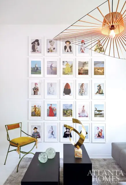 Living room with a gallery wall of framed portraits, a yellow upholstered chair, a black coffee table with glass spheres, and a modern sculpture.