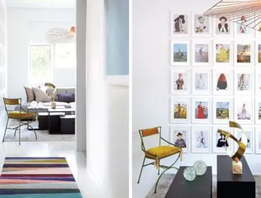 Hallway with a colorful striped rug leading to a living area with a gray sofa, windows, and a large gallery wall of framed art