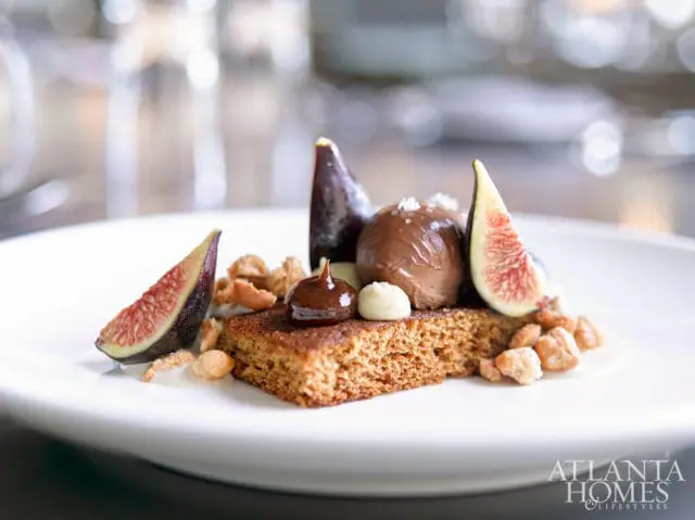 Dessert with gingerbread cake, chocolate mousse, fresh figs, and nuts, garnished with chocolate sauce and white cream