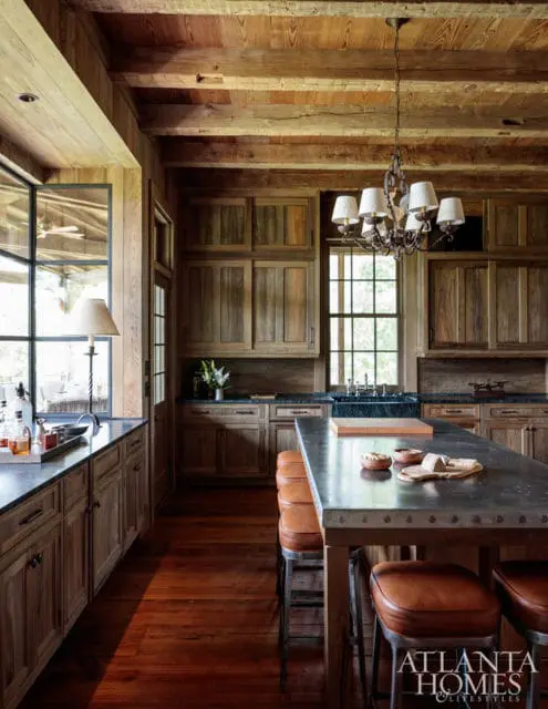 Rustic kitchen with natural wood cabinetry, beamed ceiling, and a large island with leather bar stools.