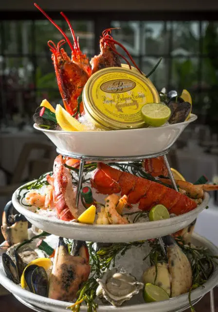 Three-tiered seafood tower with lobsters, shrimp, oysters, mussels, and a can of Royal Belgian Caviar