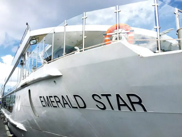 White yacht named Emerald Star with glass railings and an orange life preserver