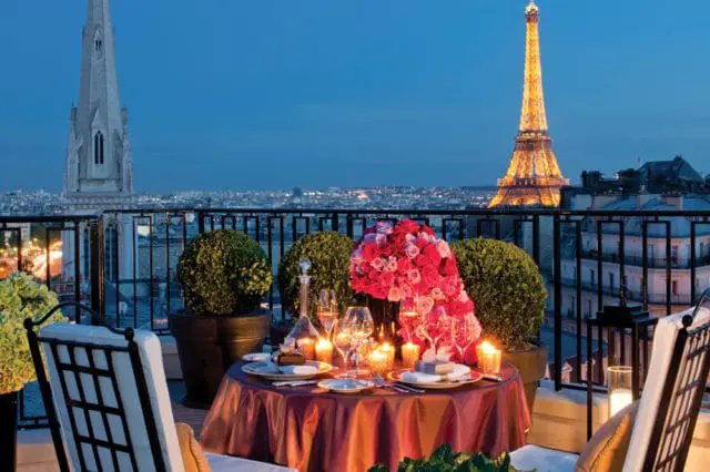 Rooftop dining table set for two with Eiffel Tower and Paris skyline at dusk