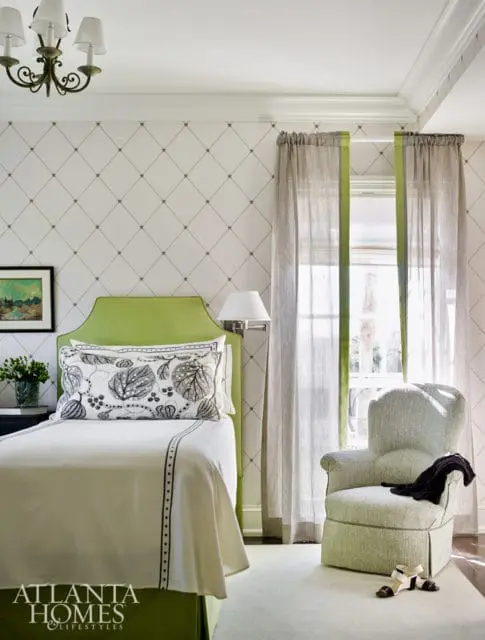 Bedroom with a lime green headboard, white bedding with black trim, patterned accent pillow, and a light green upholstered armchair.