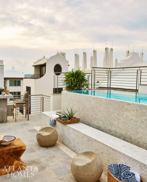 Rooftop terrace with a swimming pool, mosaic tile accents, concrete seating, and modern furniture.