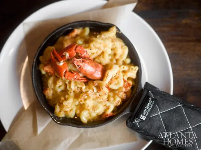 Macaroni and cheese with lobster meat served in a cast iron skillet with a San Jamar pot holder and Atlanta Homes & Lifestyles logo.