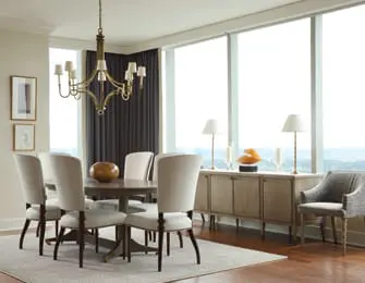 Dining room with oval wood table, upholstered chairs, buffet, and large windows with city view.