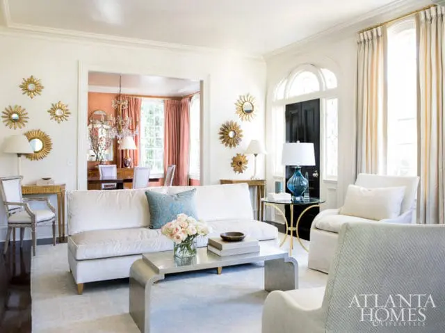 Living room with white sofa, light blue accent pillow, and metallic coffee table. A black arched door is visible in the background.