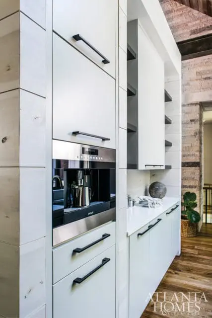 White kitchen with built-in coffee maker, white cabinetry with black hardware, and a quartz countertop