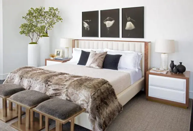 Bedroom with a tufted headboard, white bedding, a faux fur throw, and three framed ballet dancer prints above the bed.