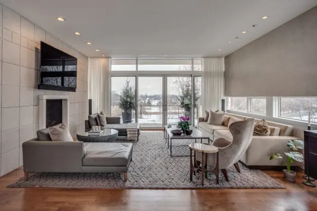 Living room with sectional sofa, leather chaise lounge, fireplace, and large windows overlooking a snowy landscape.