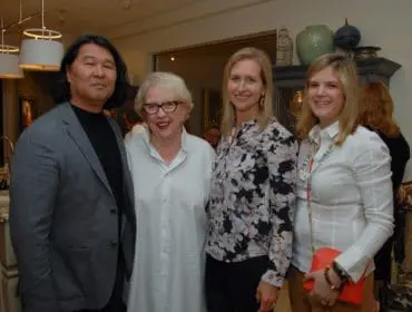 Asian man, woman in glasses, and two women smiling in a room.
