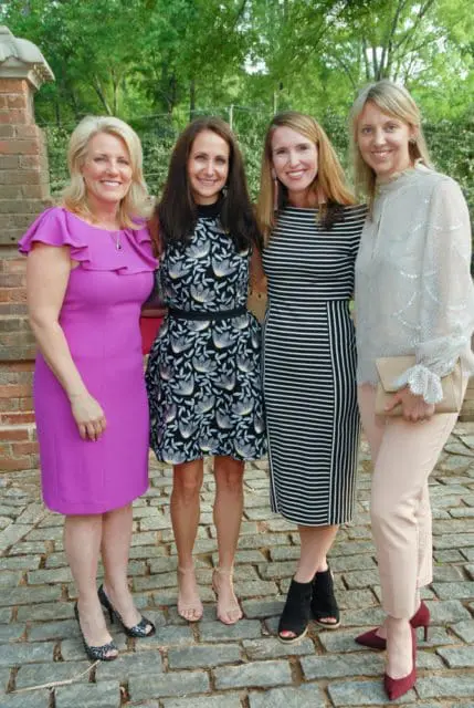 Four women posing outdoors, dressed in various outfits.