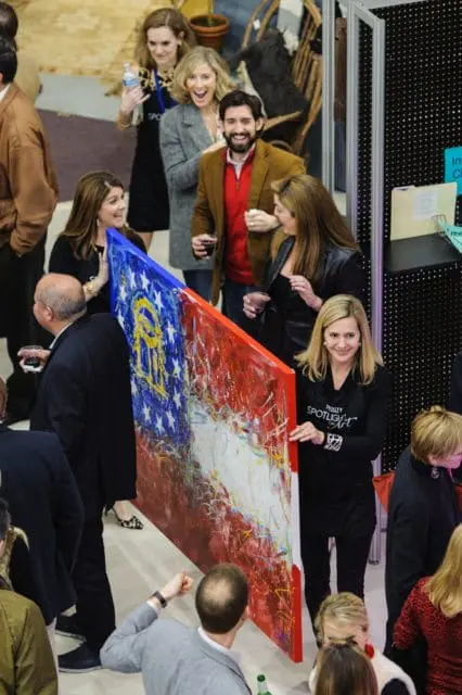 People gathered around a large abstract painting with red, white, and blue colors, featuring a depiction of the Georgia state flag.