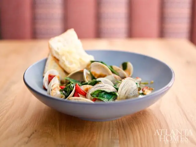 Bowl of clams with spinach, red peppers, and toasted bread, with Atlanta Homes & Lifestyles logo in the lower right corner.