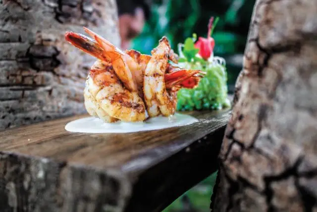 Grilled shrimp served with a dollop of white sauce and a side of green garnish