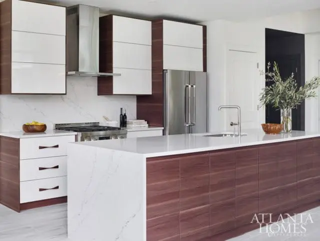 Modern kitchen with white high-gloss cabinets, dark wood lower cabinets and island, stainless steel appliances, and white quartz countertops.