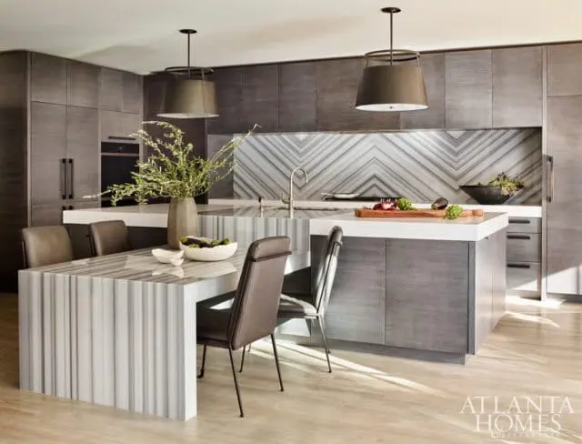 Modern kitchen with gray wood cabinetry, marble backsplash in a chevron pattern, and a marble dining table with leather chairs.