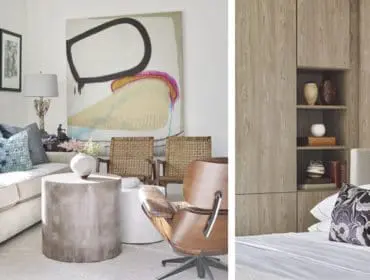 Living room with a cream sofa, concrete cylindrical coffee table, and abstract art. Adjacent is a bedroom with a bed and wood-paneled cabinetry with shelves.