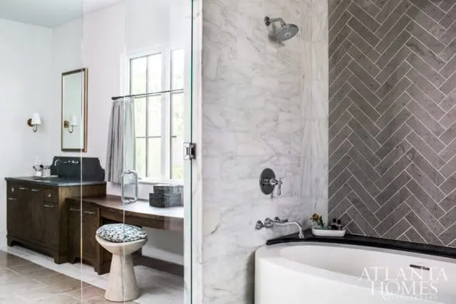 Bathroom with white marble subway tile shower, gray herringbone tile accent wall, freestanding tub, and dark wood vanity with stone countertop.