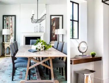 Dining room with light wood table, upholstered gray chairs, fireplace, ornate chandelier, and patterned curtains.