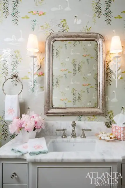 Powder room with swan and willow tree wallpaper, marble countertop, silver framed mirror, and pink peonies.
