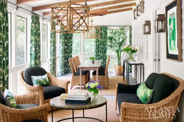 Sunroom with wicker furniture, tropical leaf print curtains, bamboo chandeliers, and a dining set.