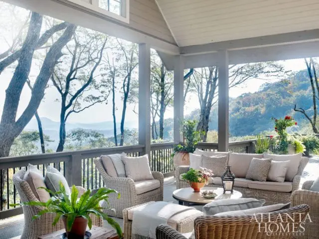 Covered porch with wicker furniture and mountain views. Includes Atlanta Homes & Lifestyles logo in the lower right corner.