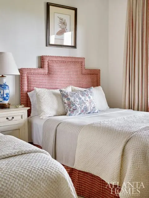 Bedroom with two beds featuring red gingham headboards and dust ruffles, white quilted bedspreads, and a patterned accent pillow.