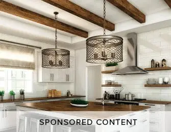 White kitchen with wood island, stainless steel appliances, white subway tile backsplash, and two industrial-style pendant lights with metal cages.