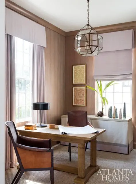 Office with wood paneled walls, a wooden desk with leather chairs, and a geometric glass pendant light.