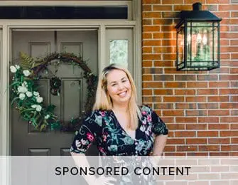 Sponsored content featuring a smiling woman in a floral dress standing in front of a brick house with a decorated front door.