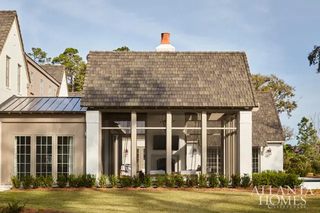 Exterior of a multi-story home with a screened-in porch, white brick accents, and a shingled roof.