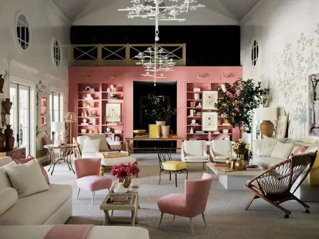 Living room with pink built-in bookshelves, white sofas, pink accent chairs, and a large white branch-like chandelier.
