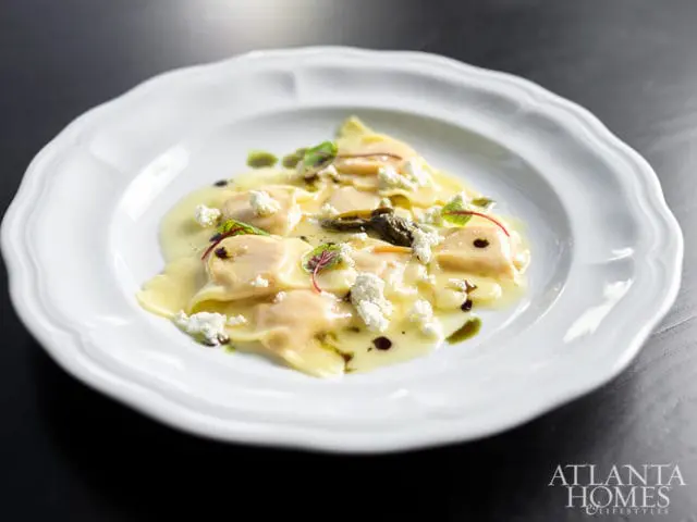 Close-up of ravioli with cheese and greens on a white plate, with Atlanta Homes & Lifestyles logo in the corner.