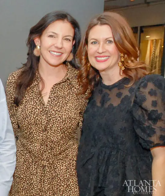 Two women smiling, one in a leopard print dress and the other in a black lace dress. The Atlanta Homes & Lifestyles logo is visible in the lower right corner.