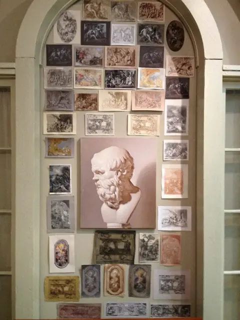Wall display featuring a bust of Socrates above a collection of framed classical etchings and prints in various sizes and tones.