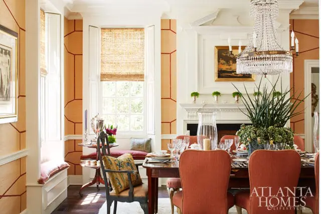 Dining room with orange geometric wallpaper, a large crystal chandelier, a fireplace, and a table set for a meal.