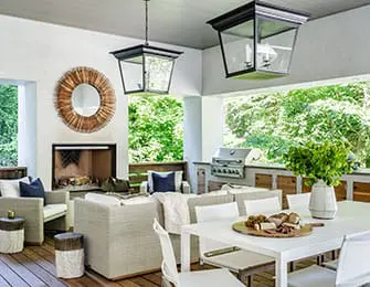 Covered outdoor living space with a fireplace, seating area, dining table, and outdoor kitchen with a grill.